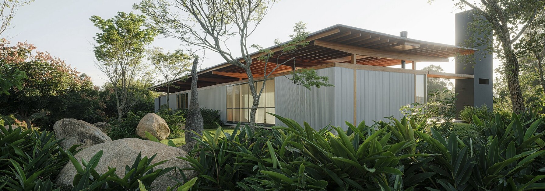 pedregulhos e árvores nativas dimensionam a pegada da casa de madeira do brasil